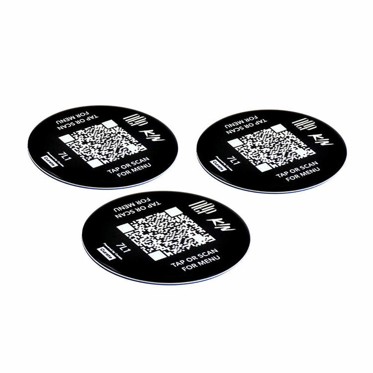 Conjunto de adesivos NFC redondos em resina epóxi com códigos QR mostrados em ângulo para destacar a cúpula brilhante e a espessura da borda.