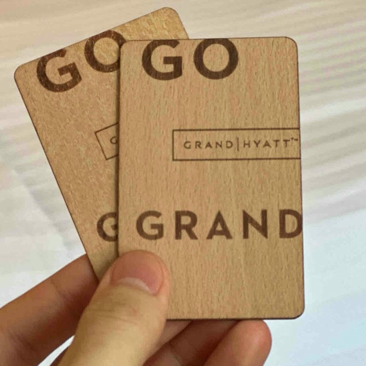 Os cartões personalizados de madeira de tília são apresentados como cartões-chave em um ambiente hoteleiro sobre uma mesa com um bloco de notas.