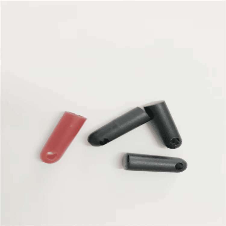 Etiquetas RFID tubulares em forma de bala vermelhas e pretas modelo SV-005 estão espalhadas sobre um fundo claro para ilustrar opções de cores para rastreamento de ativos.