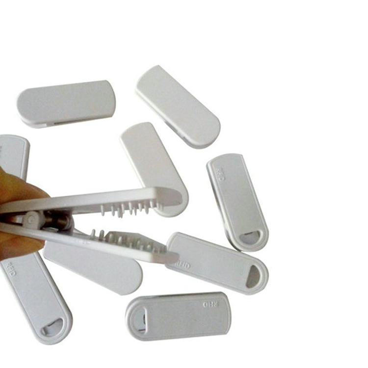 Esta imagem mostra uma pessoa abrindo a tag RFID com clipe SV-014, com várias carcaças do produto ao redor.