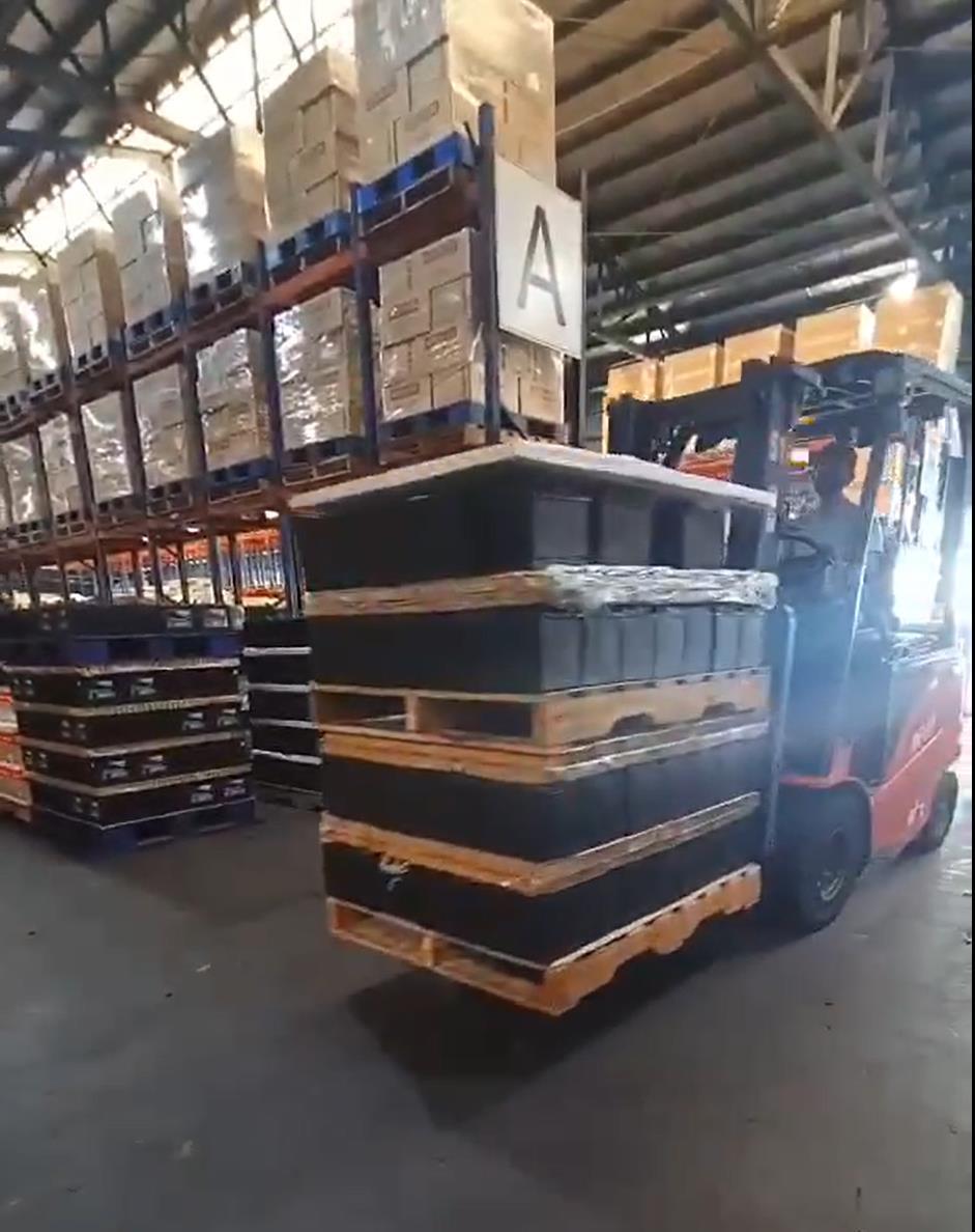 Cena de armazém com uma empilhadeira transportando paletes pelos corredores, ilustrando aplicações de rastreamento logístico com sistemas RFID fixos.