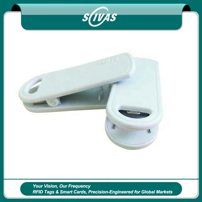 Esta imagem mostra duas tags RFID brancas com clipe SV-014 sendo que uma está aberta para exibir a estrutura de fixação para uso no inventário de varejo.