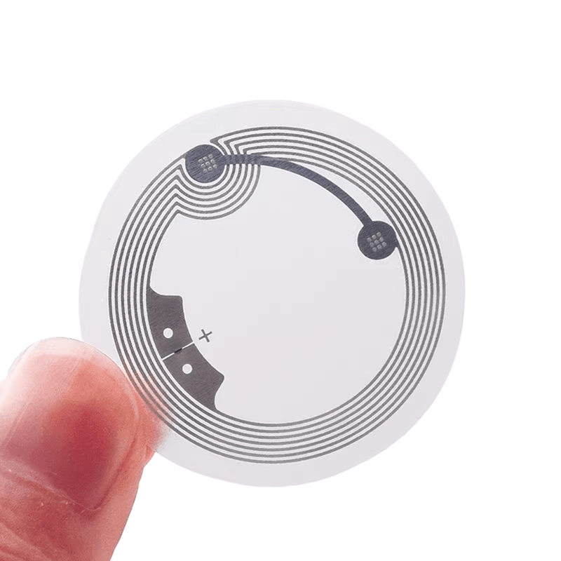 Ilustração detalhada da estrutura multicamada de uma etiqueta HF RFID resistente, incluindo a face protetora e o adesivo de alta aderência.