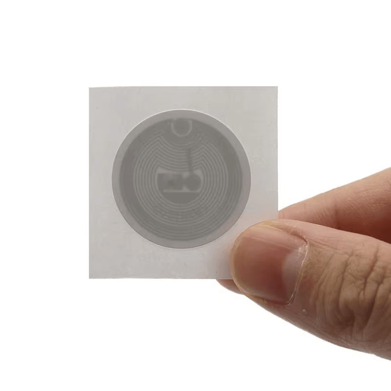 Ilustração detalhada das camadas funcionais de uma etiqueta HF RFID, incluindo face imprimível e adesivo de alta qualidade.