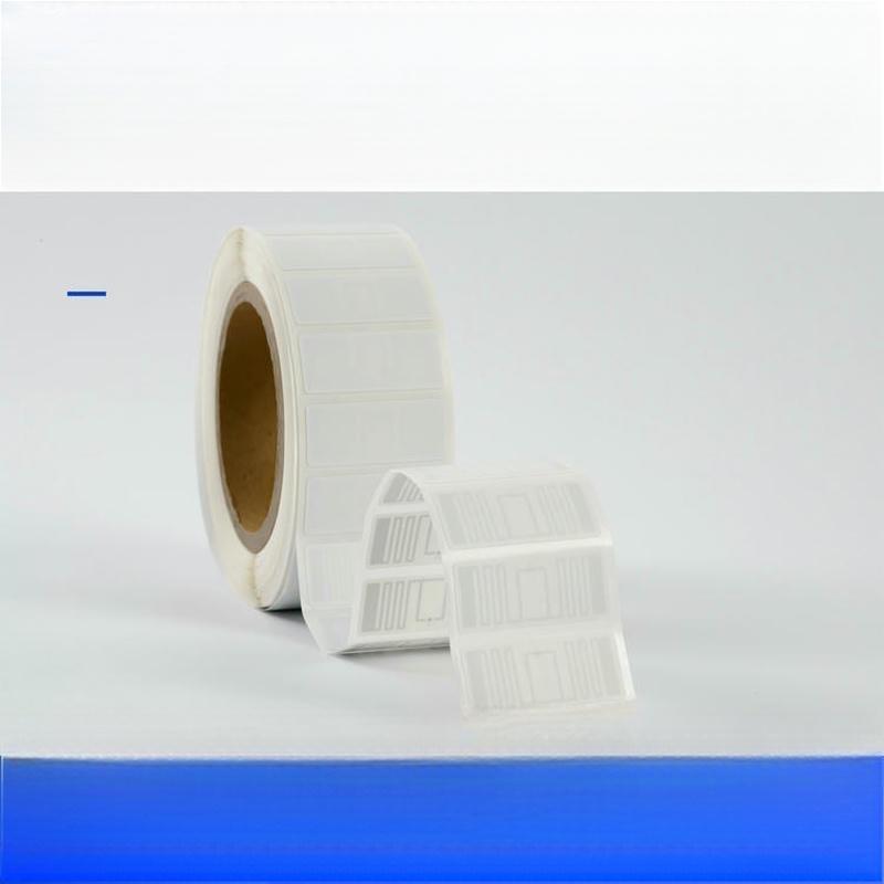 Fotografia em perspectiva de um rolo de etiquetas RFID UHF brancas, com etiquetas destacadas que revelam o desenho interno da antena.