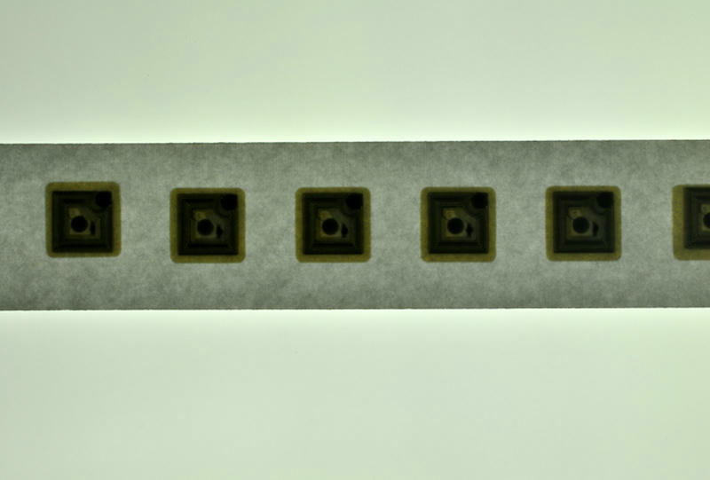 Vista aproximada da superfície branca e lisa de etiquetas RFID HF circulares sobre liner de papel, prontas para aplicações de controle de estoque no varejo.