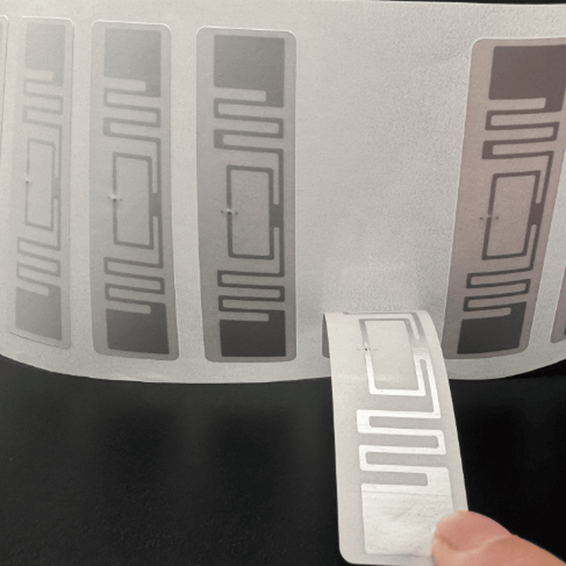 Vista da remoção mostra etiquetas RFID UHF de 70x15mm sendo desenroladas, para impressão e aplicação no rastreamento de caixas de papelão.