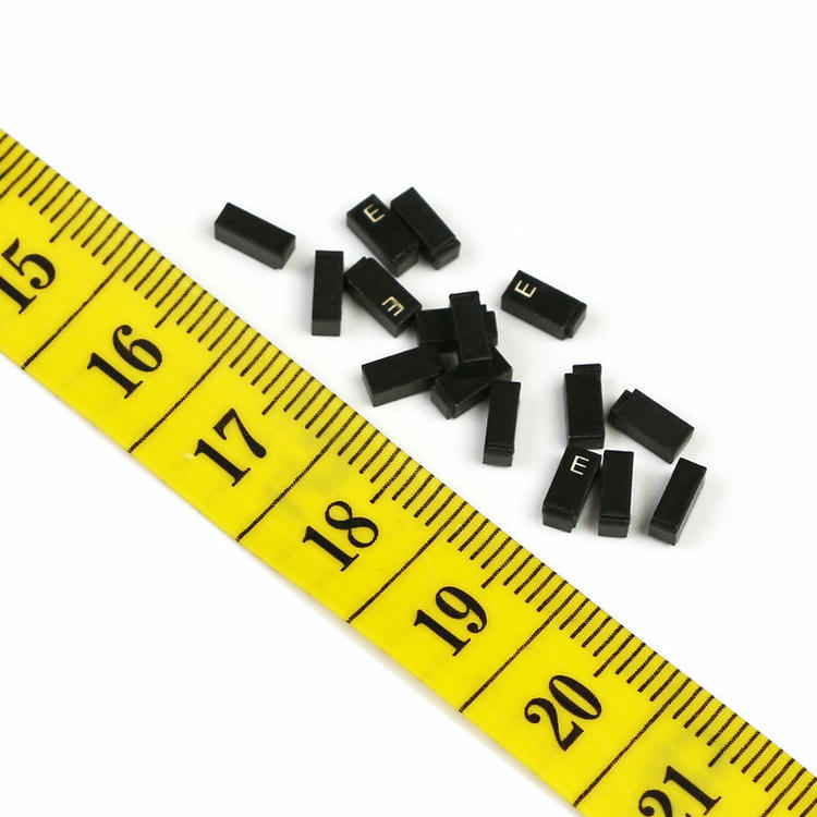 A tiny C0502-1 ceramic RFID tag is held on a fingertip to visually demonstrate its miniature 5x2.5mm dimensions.