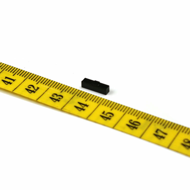 Esta imagem mostra o tamanho compacto da tag RFID cerâmica preta apoiada em um dedo destacando suas dimensões miniatura adequadas para identificar ativos estreitos como ferramentas cirúrgicas e conectores de cabos.